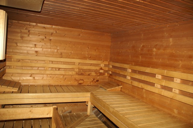Holzsauna mit Bänken an drei Wänden.